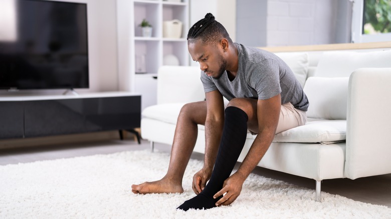 Man putting on compression sock