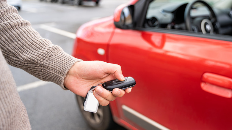 Person holding car rental key with car in background