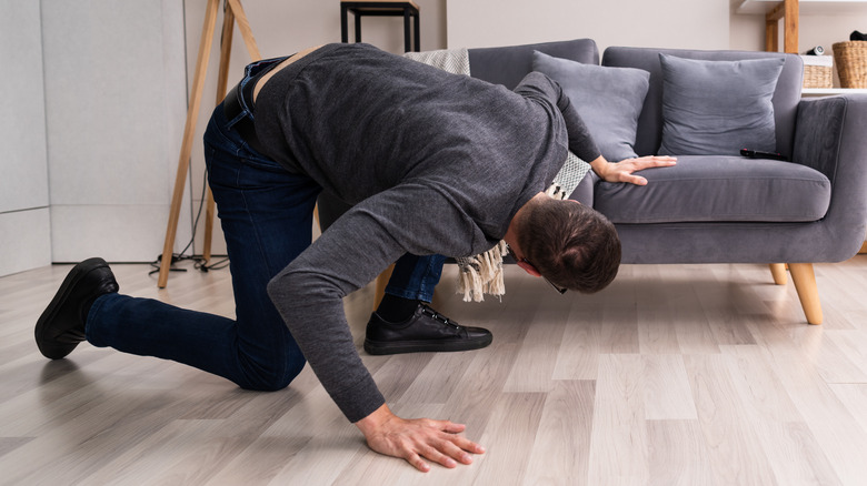 man searching under a couch