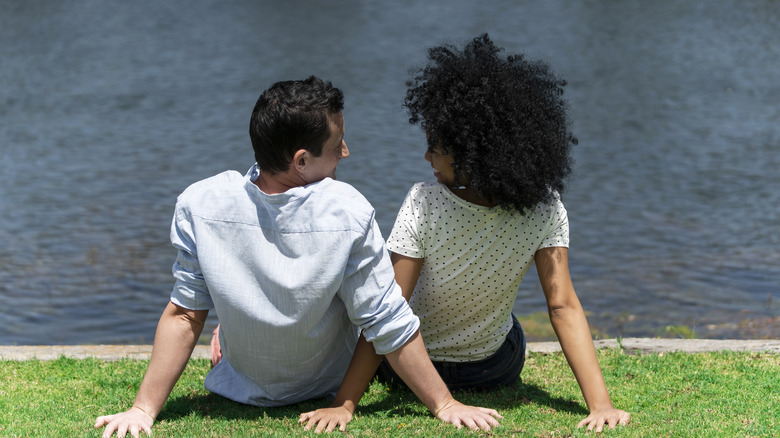 Couple sitting on grass by a lake